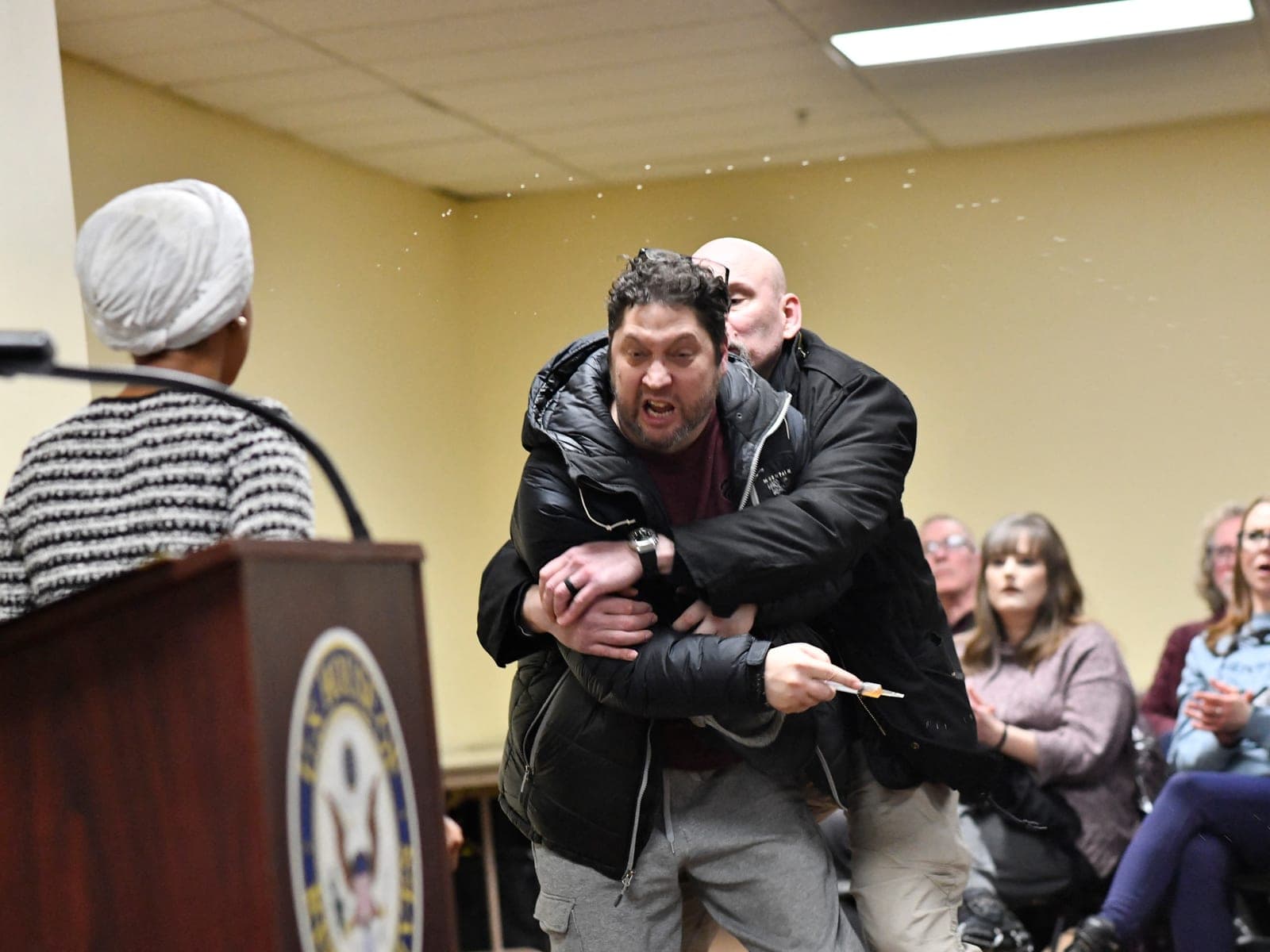 Rep. Ilhan Omar rushed by man on stage and sprayed with liquid at town hall event